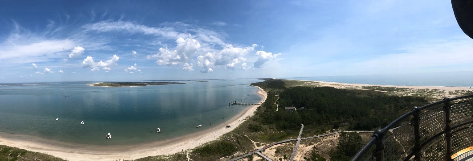 Aerial view of the Cape Lookout shoreline with a sandy beach, calm sound water and summer clouds
